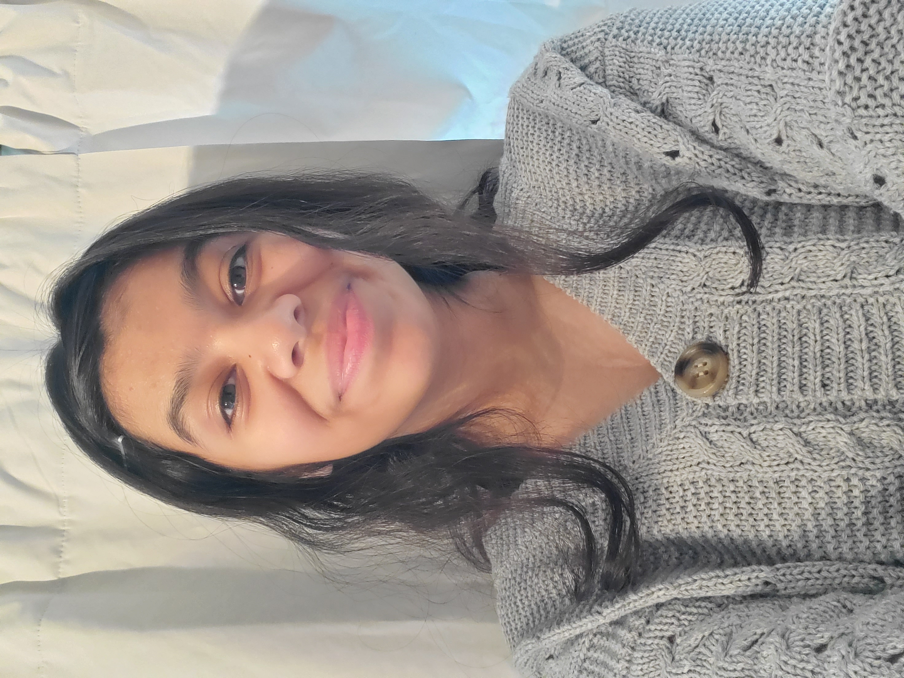 Self Photo of a girl in a gray cardigan, hair up but looses of hair framing the face